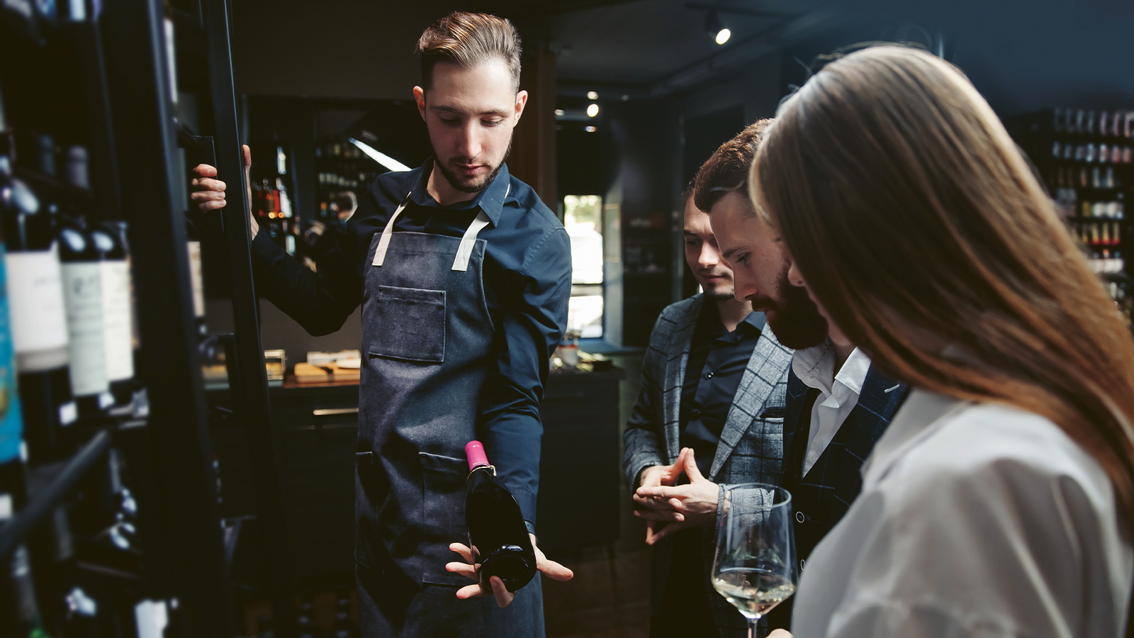 Junger Sommelier zeigt Gästen verschiedene Weine