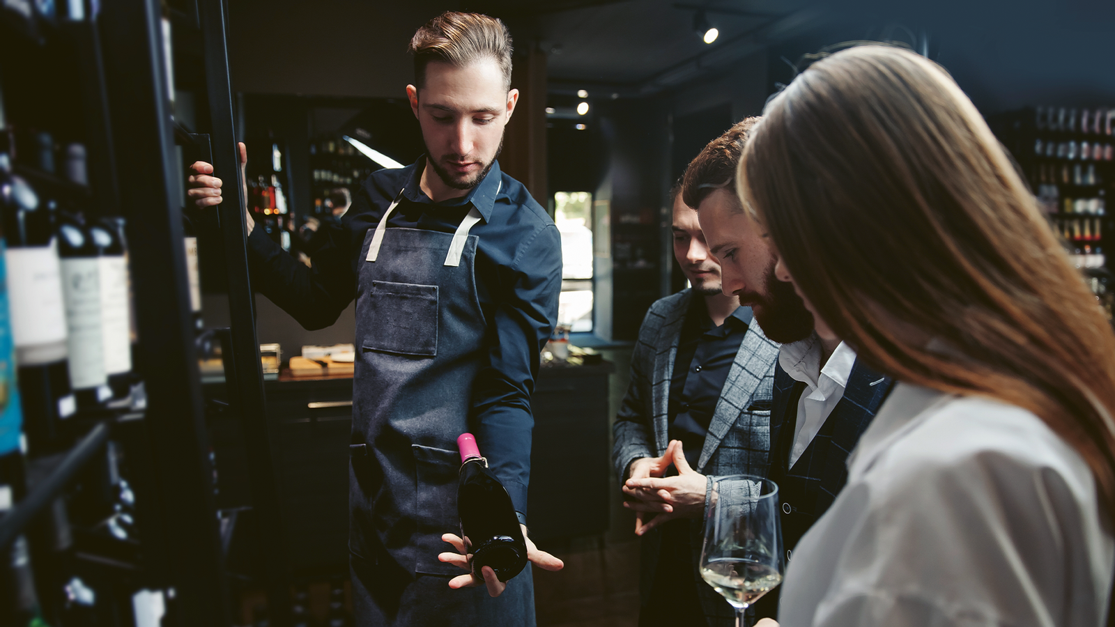 Young sommelier shows guests different wines