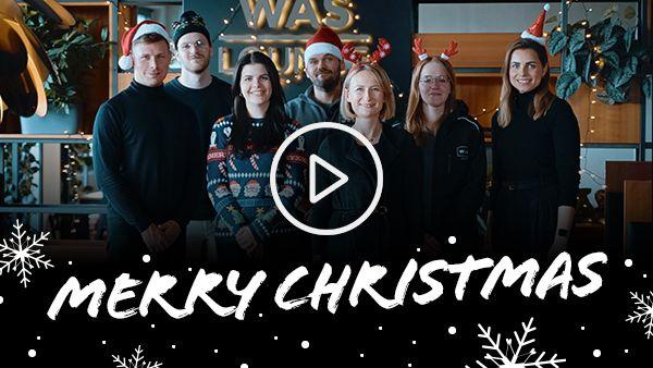 WAS Germany Team in Weihnachtsoutfits in der WAS Lounge, Merry Christmas und ein Video Play Button